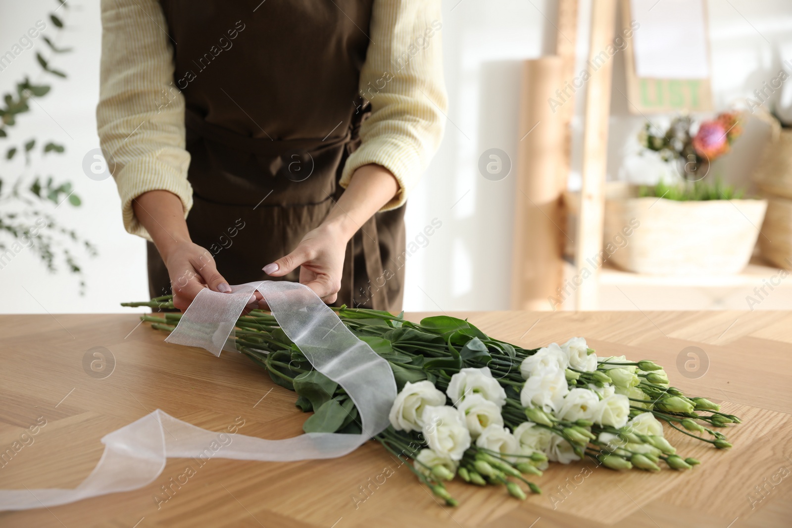 Photo of Florist making beautiful bouquet at table in workshop, closeup