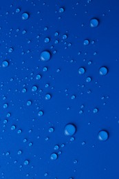 Photo of Water drops on blue background, top view