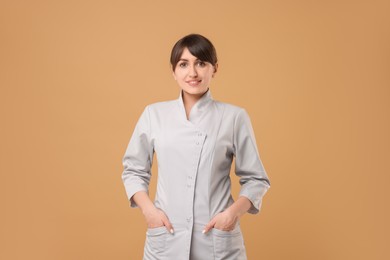 Cosmetologist in medical uniform on beige background