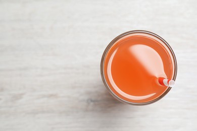 Photo of Tasty freshly made grapefruit juice on white wooden table, top view. Space for text