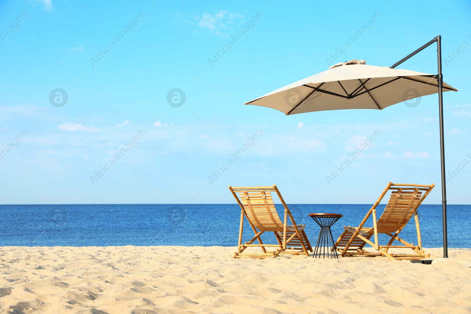 Photo of Empty wooden sunbeds and beach accessories on sandy shore