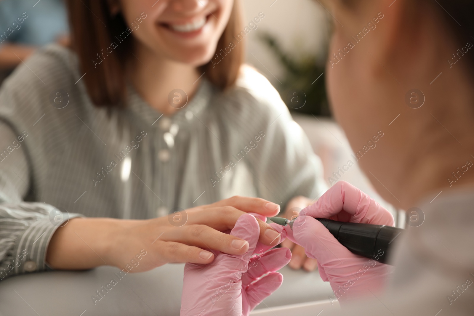 Photo of Professional manicurist working with client in beauty salon, closeup