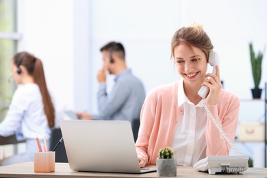 Female receptionist talking on phone at desk in office