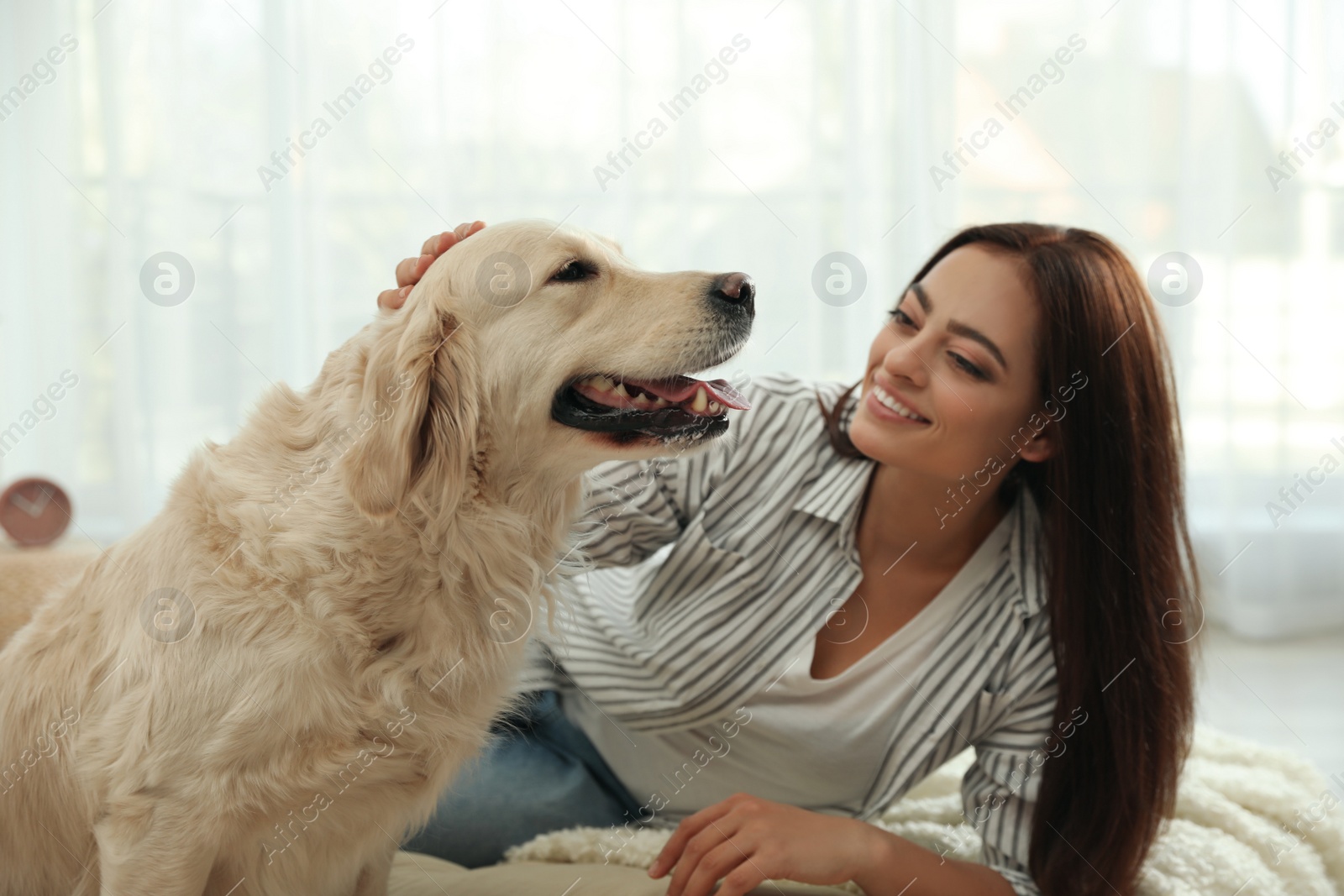 Photo of Young woman and her Golden Retriever at home. Adorable pet