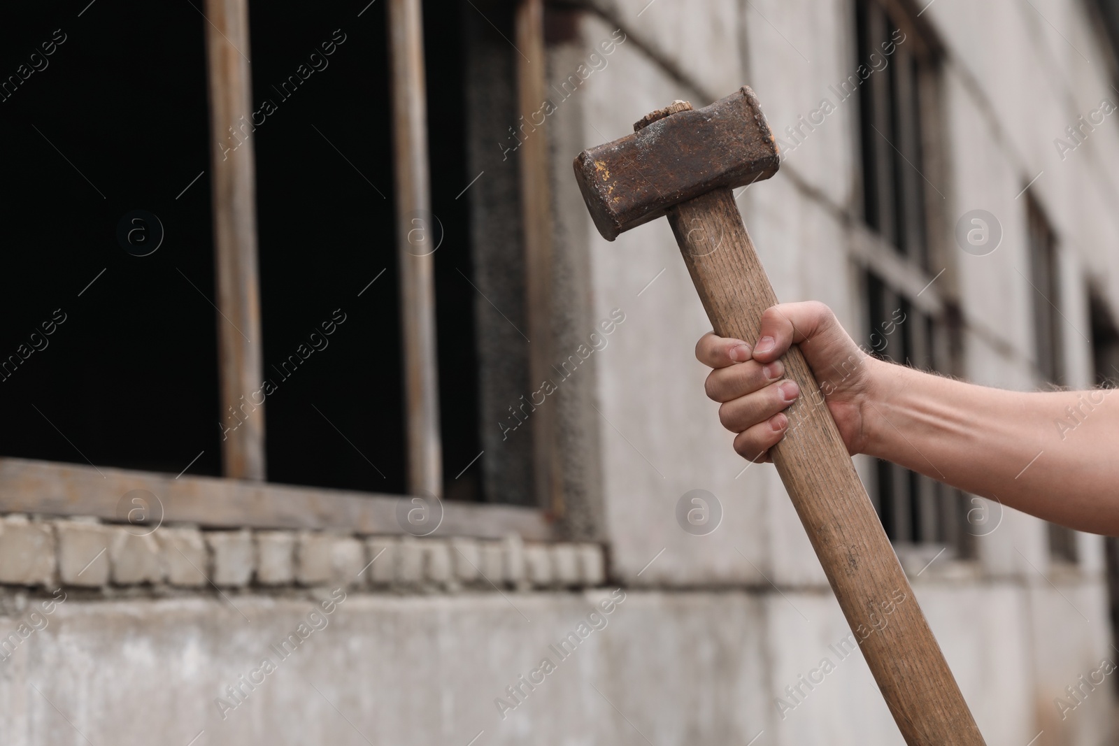 Photo of Man with sledgehammer near old building outdoors, closeup. Space for text