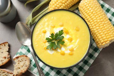 Delicious creamy corn soup served on grey table, flat lay