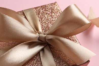 Gift box with bow on pink background, closeup