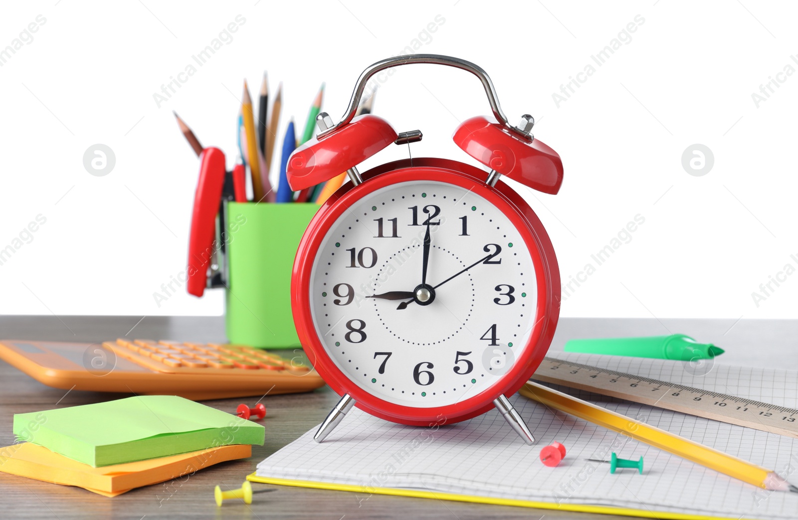 Photo of Red alarm clock and different stationery on wooden table against white background. School time