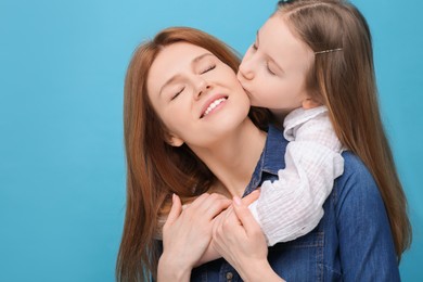 Photo of Portrait of happy mother and her cute daughter on light blue background. Space for text