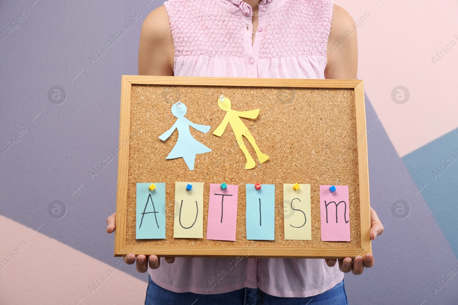 Photo of Woman holding board with word "Autism" on color background