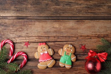 Photo of Flat lay composition with gingerbread couple on wooden table, space for text