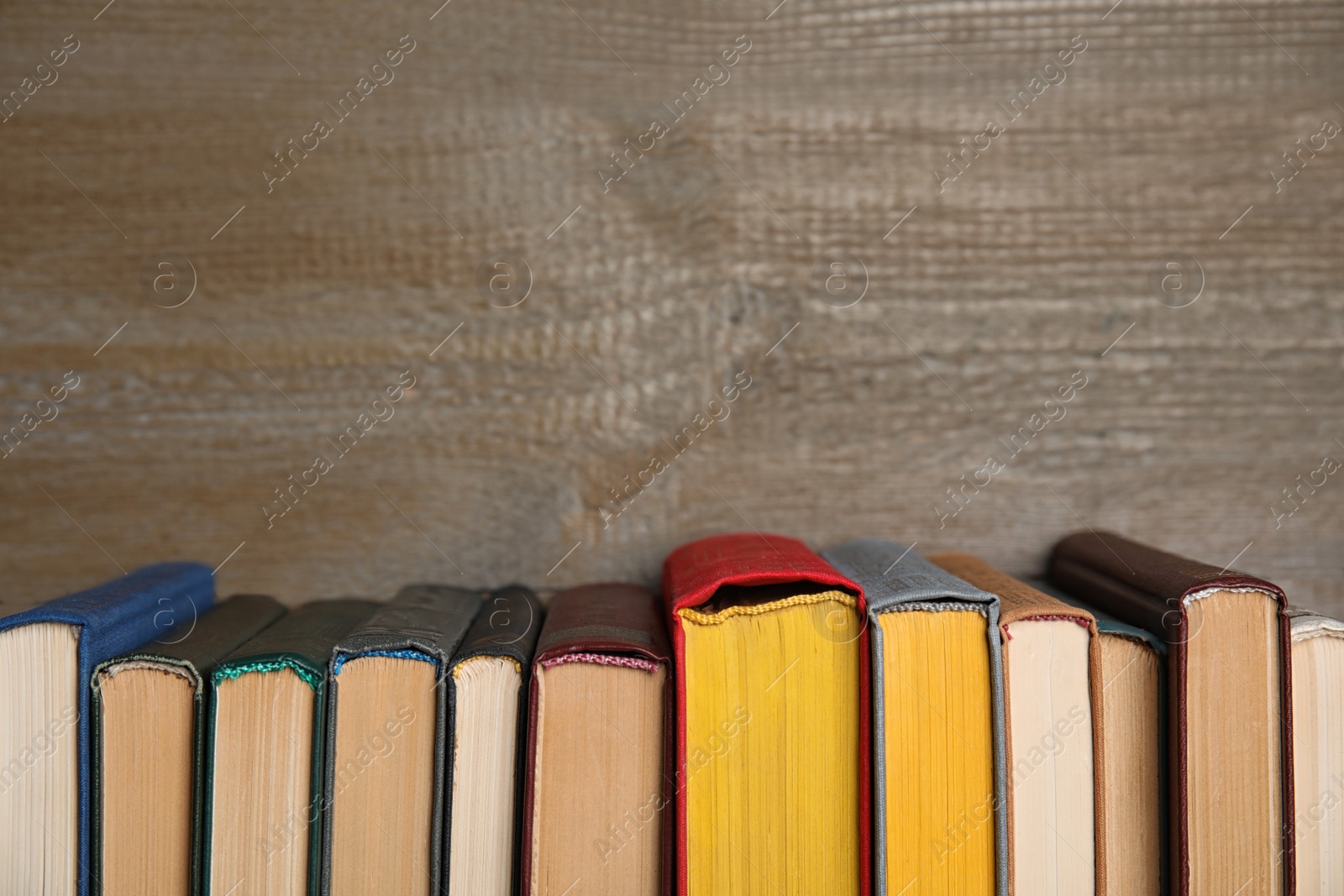 Photo of Stack of hardcover books on wooden background. Space for text