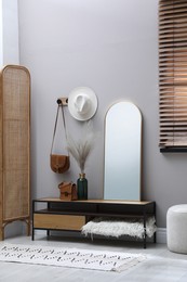 Stylish hallway interior with mirror and table near light wall