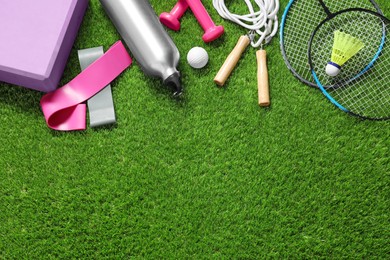 Photo of Different sport tools on green grass, flat lay. Space for text