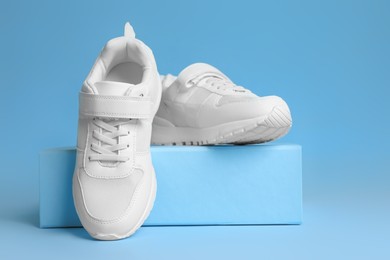 Pair of stylish sneakers and box on light blue background