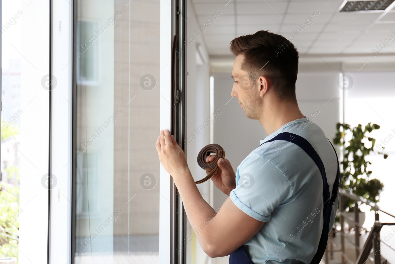 Photo of Construction worker putting sealing foam tape on window indoors