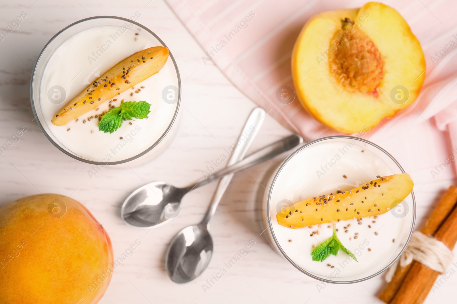 Photo of Tasty peach dessert with yogurt and chia seeds served on white wooden table, flat lay