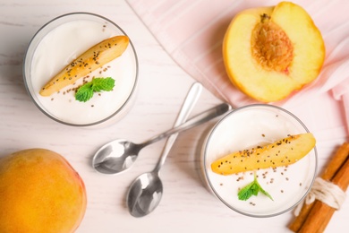 Photo of Tasty peach dessert with yogurt and chia seeds served on white wooden table, flat lay