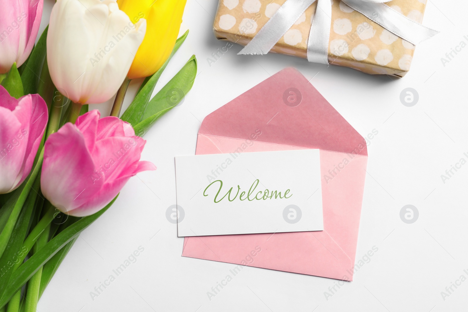 Image of Welcome card, envelope, gift box and beautiful tulips on white background, flat lay