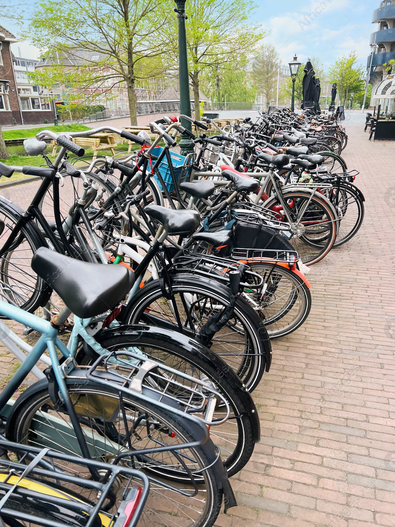 Photo of Many different bicycles parked on sidewalk, closeup
