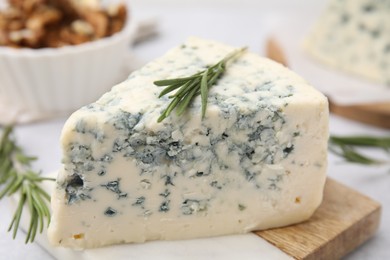 Tasty blue cheese with rosemary on light table, closeup
