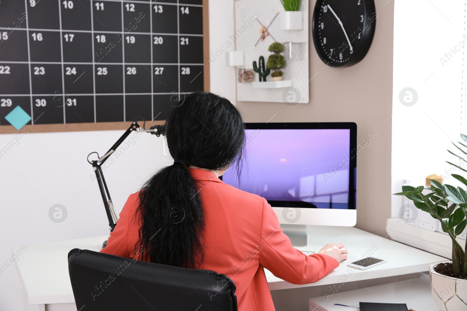 Photo of Young woman working with computer at desk in office