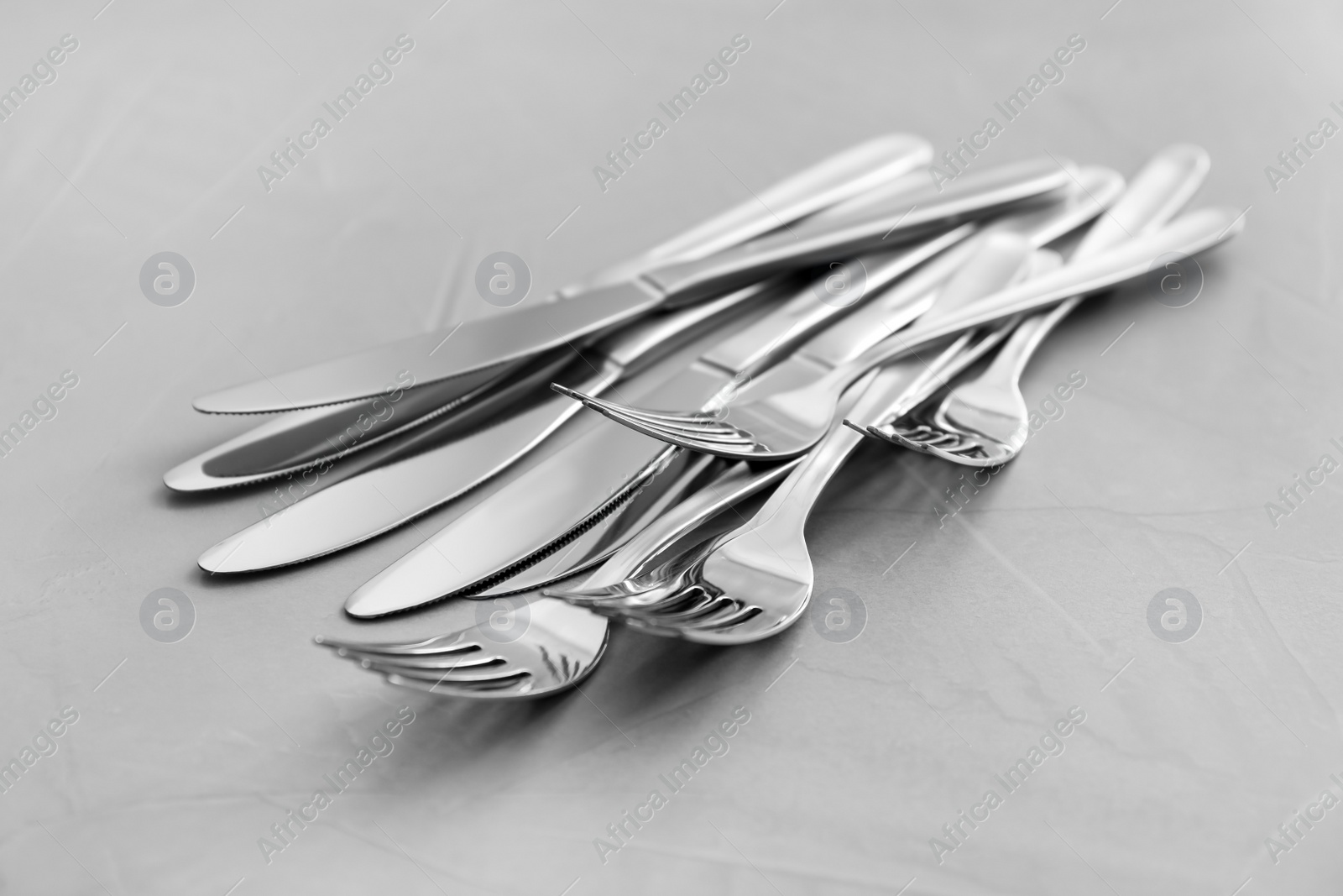 Photo of Knives and forks on light grey table, closeup