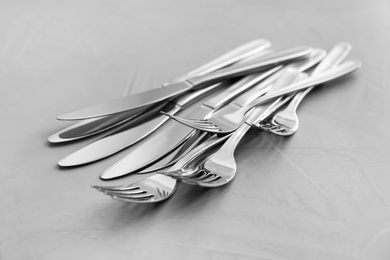 Photo of Knives and forks on light grey table, closeup