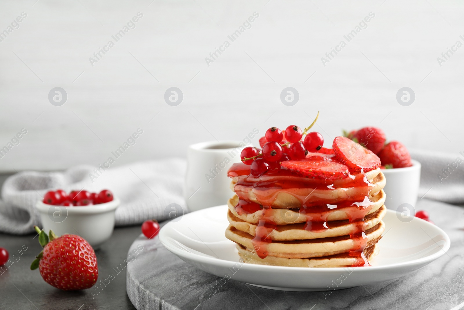 Photo of Delicious pancakes with fresh berries and syrup on grey table