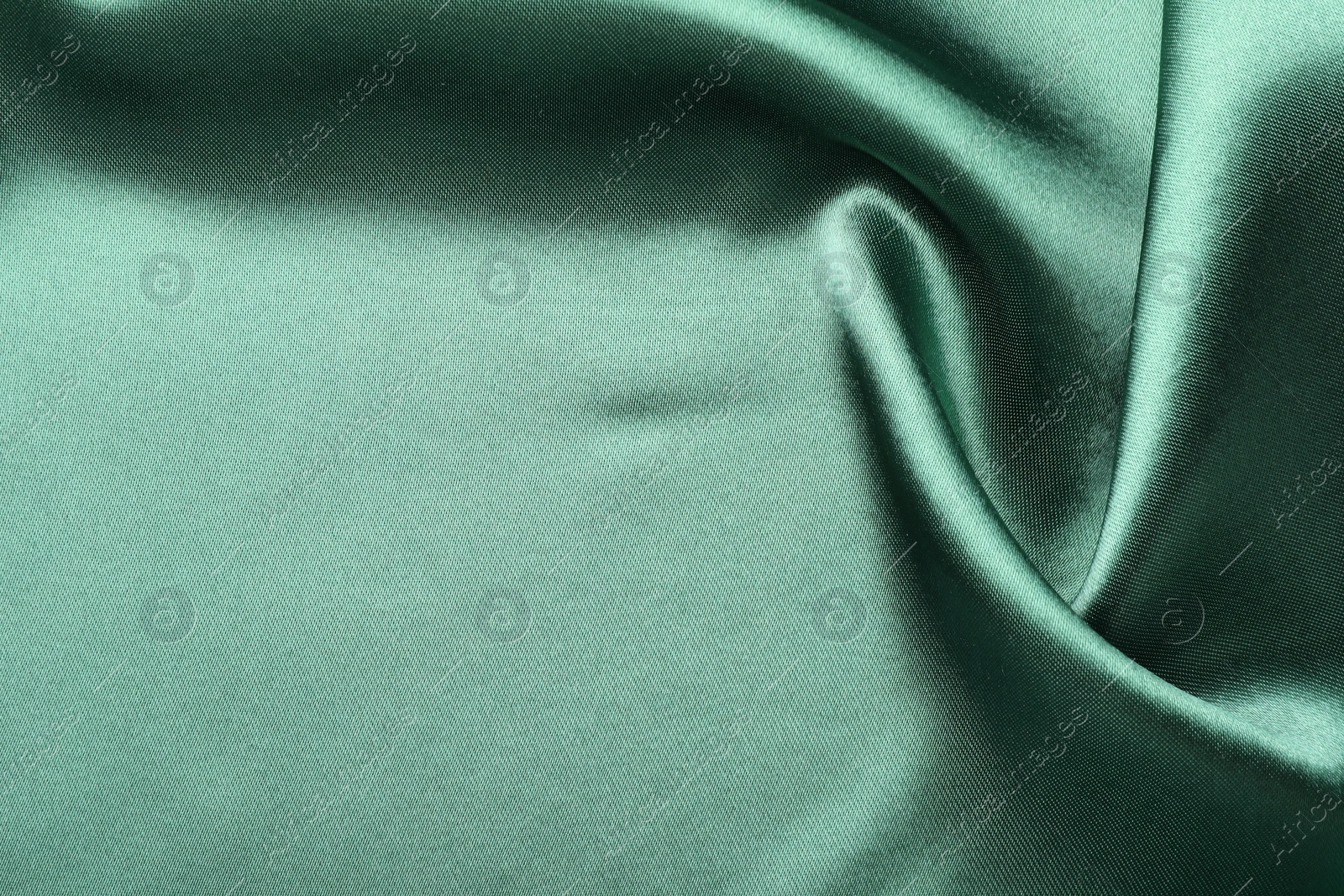 Photo of Crumpled green silk fabric as background, top view. Space for text