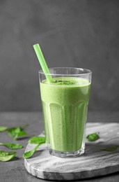 Photo of Glass of healthy green smoothie with fresh spinach on grey table