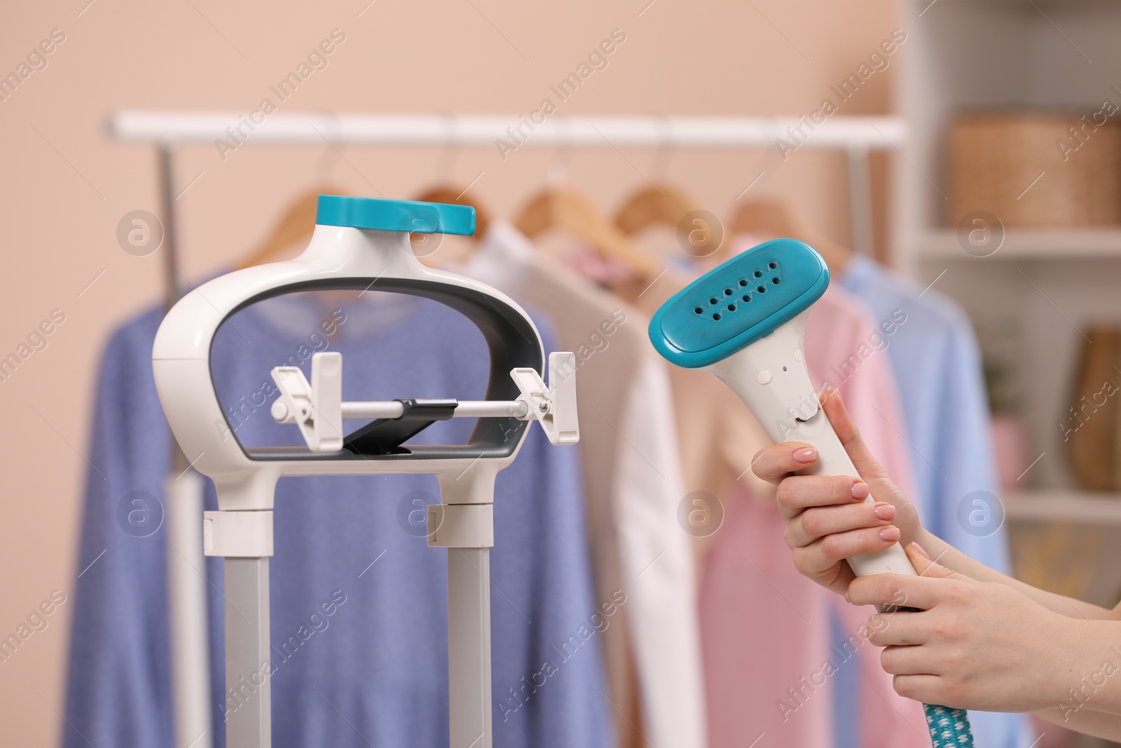 Photo of Woman with modern steam iron at home, closeup