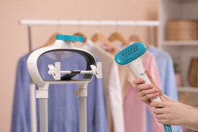 Woman with modern steam iron at home, closeup