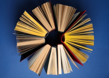 Circle made of hardcover books on blue background, flat lay