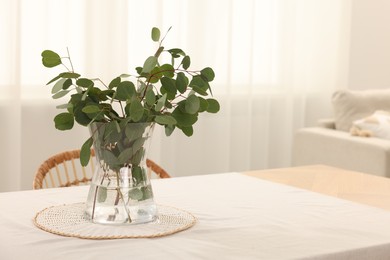 Photo of Vase with eucalyptus branches on table in dining room. Space for text