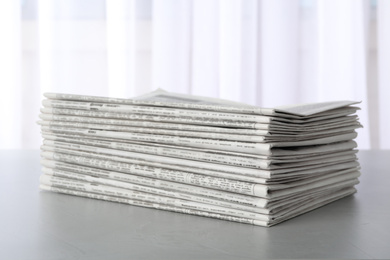 Stack of newspapers on light grey table. Journalist's work