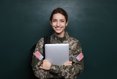 Female cadet with backpack and laptop near chalkboard. Military education