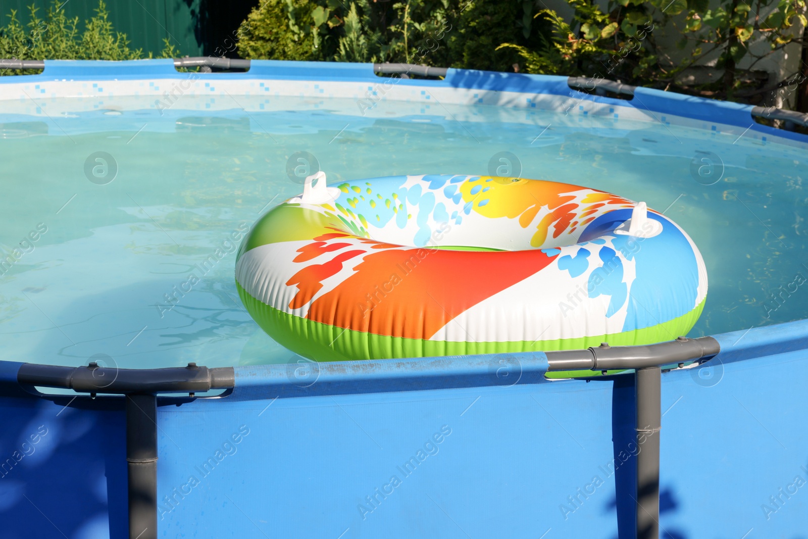 Photo of Inflatable ring floating on water in above ground swimming pool outdoors