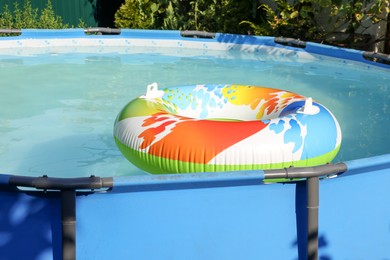 Photo of Inflatable ring floating on water in above ground swimming pool outdoors