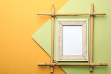 Photo of Empty bamboo frame on color background, top view. Space for text