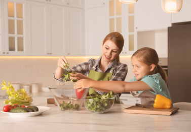 Mother and daughter cooking salad together in kitchen