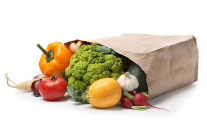 Overturned paper bag with vegetables on white background