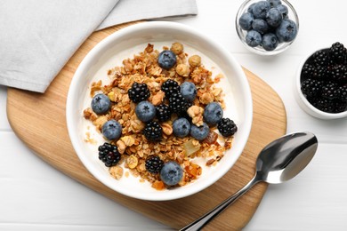 Bowl of healthy muesli served with berries on white wooden table, flat lay