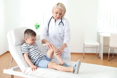 Photo of Doctor examining little patient with knee problem in clinic