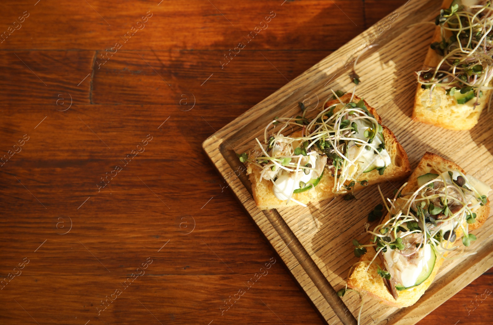 Photo of Delicious bruschettas with fish on wooden table, top view. Space for text