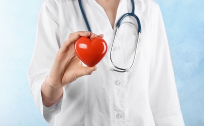 Photo of Female doctor holding heart model on light background. Cardiology service