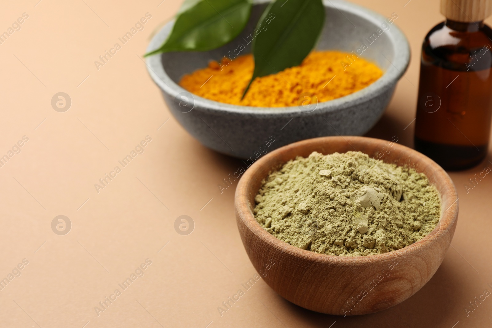 Photo of Bottle, henna and turmeric powder on coral background, space for text. Natural hair coloring