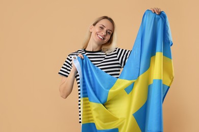 Photo of Happy woman with flag of Sweden on beige background