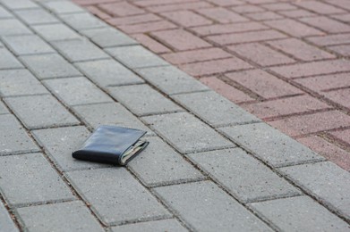 Photo of Black wallet on pavement outdoors, space for text. Lost and found