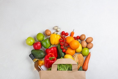 Photo of Flat lay composition with overturned paper bag and groceries on white table